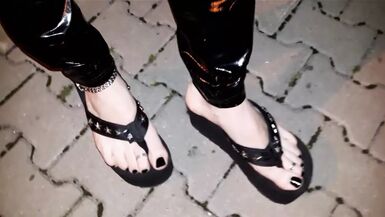 crossdresser on a public street in latex leggings and sexy platform flip flops - 1 image